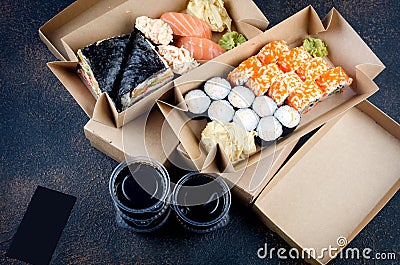 Tasty sushi rolls in disposable kraft paper boxes, sauces, chopsticks. Food for take away or delivery Stock Photo