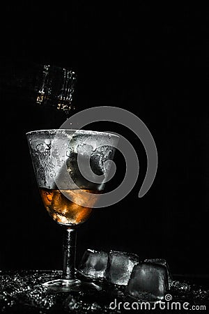 Tasty wine pouring in beautiful misted vintage glass with pieces of ice Stock Photo
