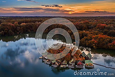 Tata, Hungary - Beautiful autumn sunset over wooden fishing cottages on a small island at Lake Derito Derito-to in October Stock Photo