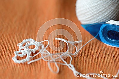 Tatting lace in the manufacturing process. Fragment of lace and shuttle on textile background close-up. Hobbies and leisure Stock Photo