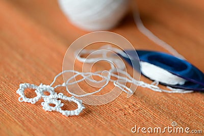 Tatting lace in the manufacturing process. Fragment of lace and shuttle on textile background close-up. Hobbies and leisure Stock Photo