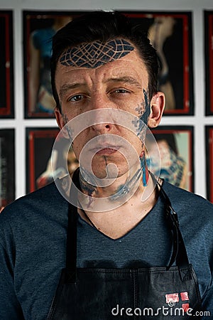 Tattoo artist in black leather apron in studio Stock Photo