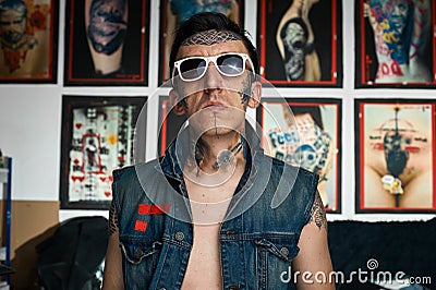 Tattoo artist in denim vest in studio Stock Photo