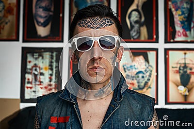 Tattoo artist in denim vest and sunglasses Stock Photo