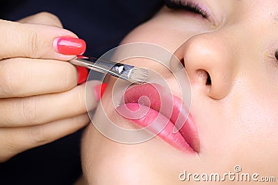 tattoo artist holds a brush in his hand and smears a foundation near his lips correcting the finished tattoo work Stock Photo