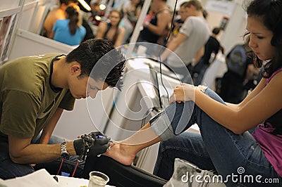 Tattoo artist tatooing the client body at the shop Editorial Stock Photo