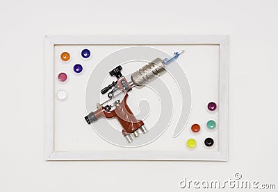 Tattoo machine on a white background, white frame, colored tattoo ink in plastic jars. The view from the top. Stock Photo