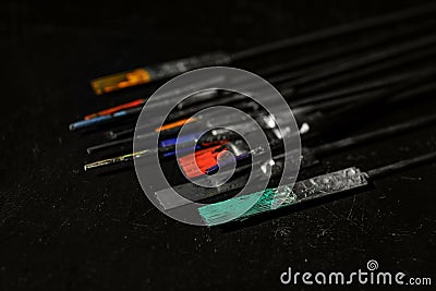 Tattoo needles covered with colorful inks on black, closeup Stock Photo