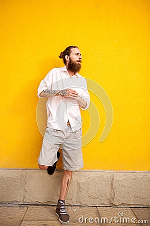 Tattooed bearded attractive man on yellow wall Stock Photo