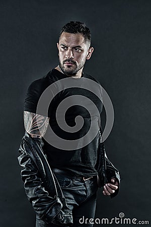 Tattooed man in tshirt and leather jacket. Bearded man show tattoo on strong arm. Fashion macho with beard on unshaven Stock Photo