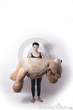 Tattooed natual looking woman playing with giant teddy bear Stock Photo