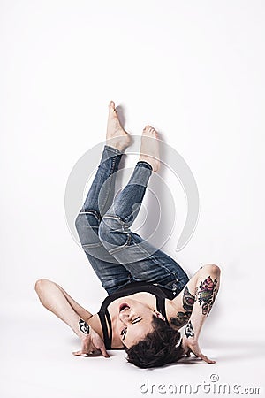 Tattooed natual looking woman with short black hair lying down on bright background Stock Photo