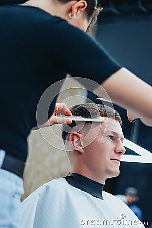 A tattooed woman hairdresser cuts guy& x27;s hair Stock Photo