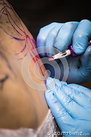 Tattooer showing process of making a tattoo, hands holding a tatoo machine Stock Photo