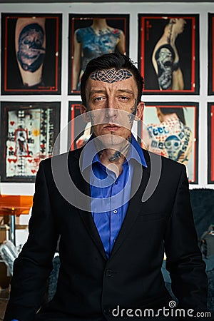 Tattooist in black jacket and blue shirt in studio Stock Photo