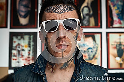 Tattooist in denim vest and sunglasses Stock Photo