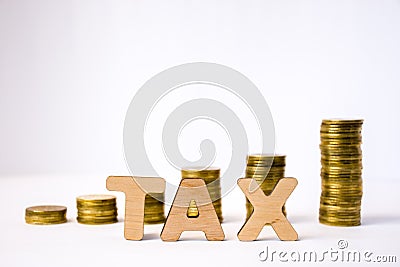 Tax concept photo. Tax word from 3D volumetric letters is in foreground to background of blurred columns or stacks of coins in exi Stock Photo