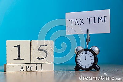 Tax Day Reminder Concept. 15 april wooden calendar and alarm clock with banner and handwritten phrase Stock Photo