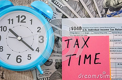 Tax form 1040, alarm clocks dollars on a wooden table. Close-up. Business concept. Editorial Stock Photo