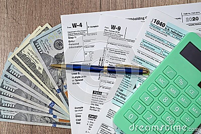 tax forms 1040 are blank to fill out and dollars are sloppily scattered on a wooden table. Editorial Stock Photo