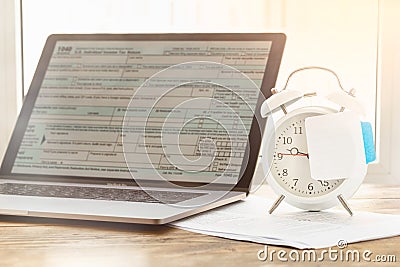 Tax planning. Laptop with form individual income tax returns with post-it alarm clock Stock Photo