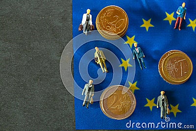 Figurines of people and euro coins on European union flag. Stock Photo