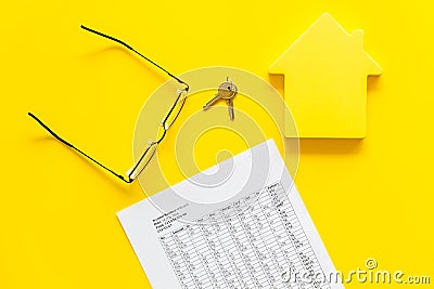Tax for property accounting with house figure, keys, table, glasses on yellow background top view Stock Photo