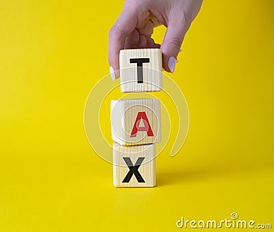 Tax symbol. Wooden cubes with word Tax. Businessman hand. Beautiful yellow background. Business and Finace and Tax concept. Copy Stock Photo