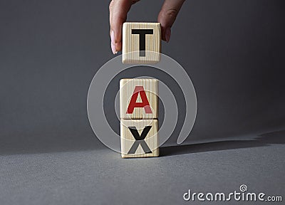 Tax symbol. Wooden cubes with word Tax. Businessman hand. Beautiful grey background. Business and Finace and Tax concept. Copy Stock Photo