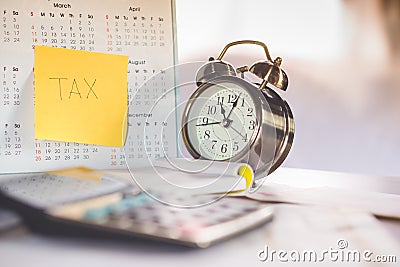 Tax word note on calendar, alarm clock and calculator on table Stock Photo
