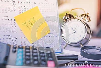 Tax word note on calendar, alarm clock and calculator on table Stock Photo