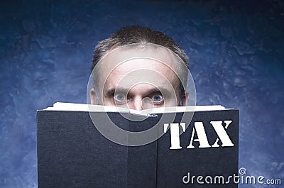 TAX written on the cover of the book, mature man being focused and hooked by book, reading open book, surprised young man Stock Photo
