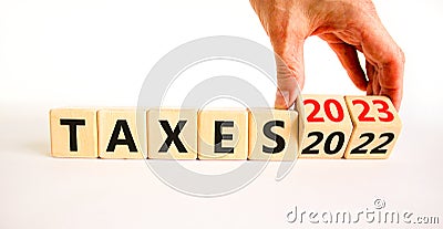 2023 taxes new year symbol. Businessman turns a wooden cube and changes words Taxes 2022 to Taxes 2023. Beautiful white table Stock Photo