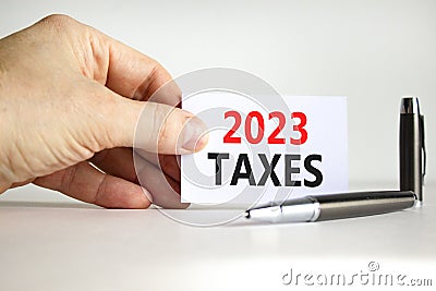 2023 taxes new year symbol. White paper with words 2023 taxes. Businessman hand. Metallic pen. Beautiful white table white Stock Photo