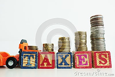 Taxes word on wooden cubes with scale of money above pushed by orange forklift Stock Photo