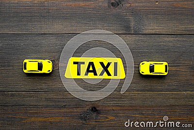 Taxi concept. Yellow service sign text taxi near car toy on dark wooden background top view copy space Stock Photo
