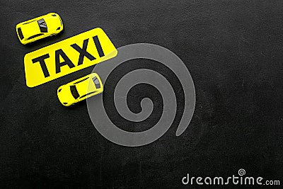 Taxi concept. Yellow service sign text taxi near car toy on black background top view copy space Stock Photo