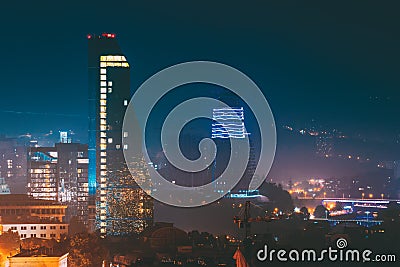 Tbilisi, Georgia. Construction Development Of Modern Architecture On Background Of Urban Night Cityscape. Evening Night Stock Photo