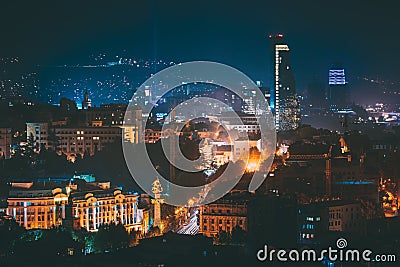 Tbilisi, Georgia. Construction Development Of Modern Architecture On Background Of Urban Night Cityscape. Evening Night Stock Photo