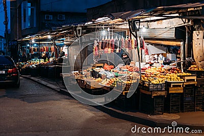 Tbilisi, Georgia - March 28, 2022: View On Night Fruit City Market In Tbilisi. Tired Seller Dozed Off At Night In Market Editorial Stock Photo