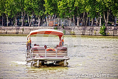 Tbilisi Georgia - Pontoon boat with female passengers in headscarves on Mtkvari - Kura River with retaining wall and Editorial Stock Photo