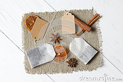 Tea bags, anise, cinnamon sticks and slices of dried tangerines. Lying on a piece of linen. Against the background of white Stock Photo