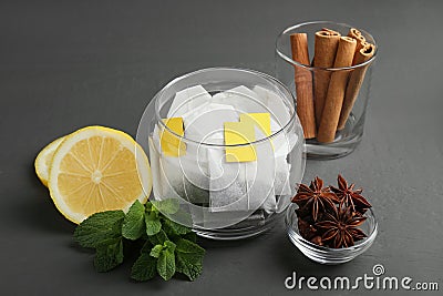 Tea bags, anise stars, cinnamon sticks, mint and lemon on grey wooden table Stock Photo