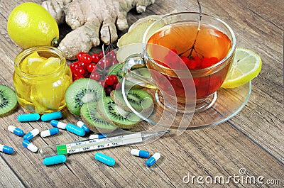 Tea for cold and flu. Vitamin tea, honey, ginger, lemons and viburnum. Thermometer and tablets. Stock Photo