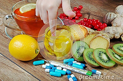 Tea for cold and flu. Vitamin tea, honey, ginger, lemons and viburnum. Thermometer and tablets. Stock Photo
