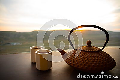 Tea concept. Japanese tea ceremony culture east beverage. Teapot and cups on table with bamboo leaves on sunset Stock Photo