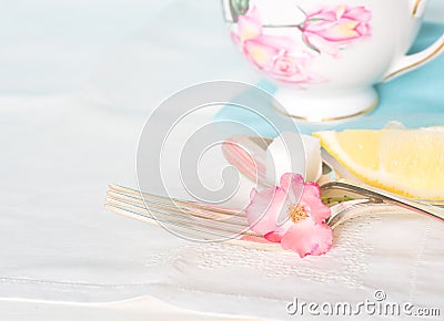 Tea Cup, Fork and Spoon with sugar cube and lemon on white table cloth Stock Photo