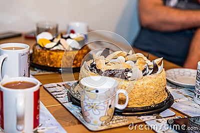 Tea cups mugs with two dessert cake tarts on wooden table at home Stock Photo