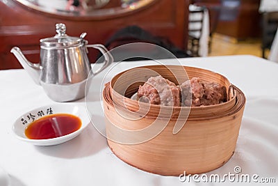 Tea & dim sum on a white table : Iron kettle, Dim Sum bambou basket steamed beef balls Stock Photo