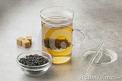 Tea glass with green gunpowder tea and a bowl with dried tea leaves Stock Photo